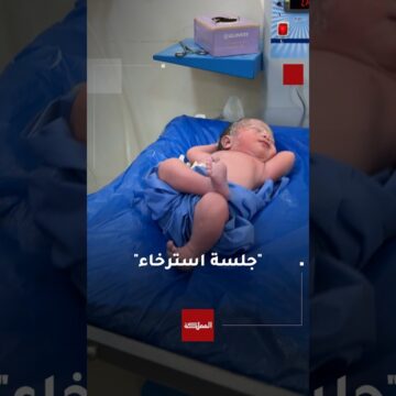 طبيب يوثق طفلا حديث الولادة وهو مستلقٍ بوضعية طريفة